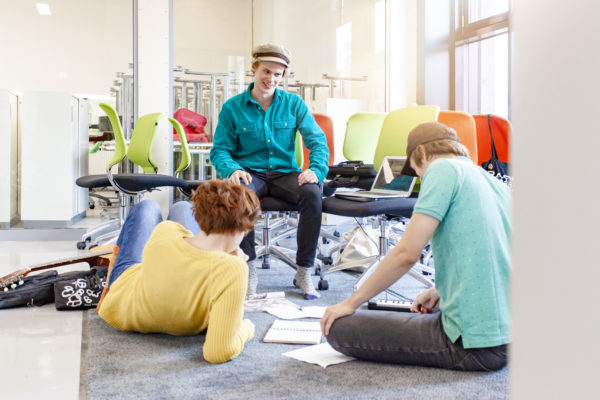 Kolme ihmistä opiskelemassa lattialla.