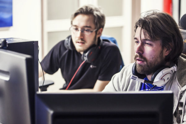 Kaksi miestä tietokoneiden edessä.