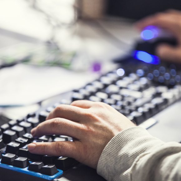 Henkilön kädet tietokoneen näppäimistöllä.