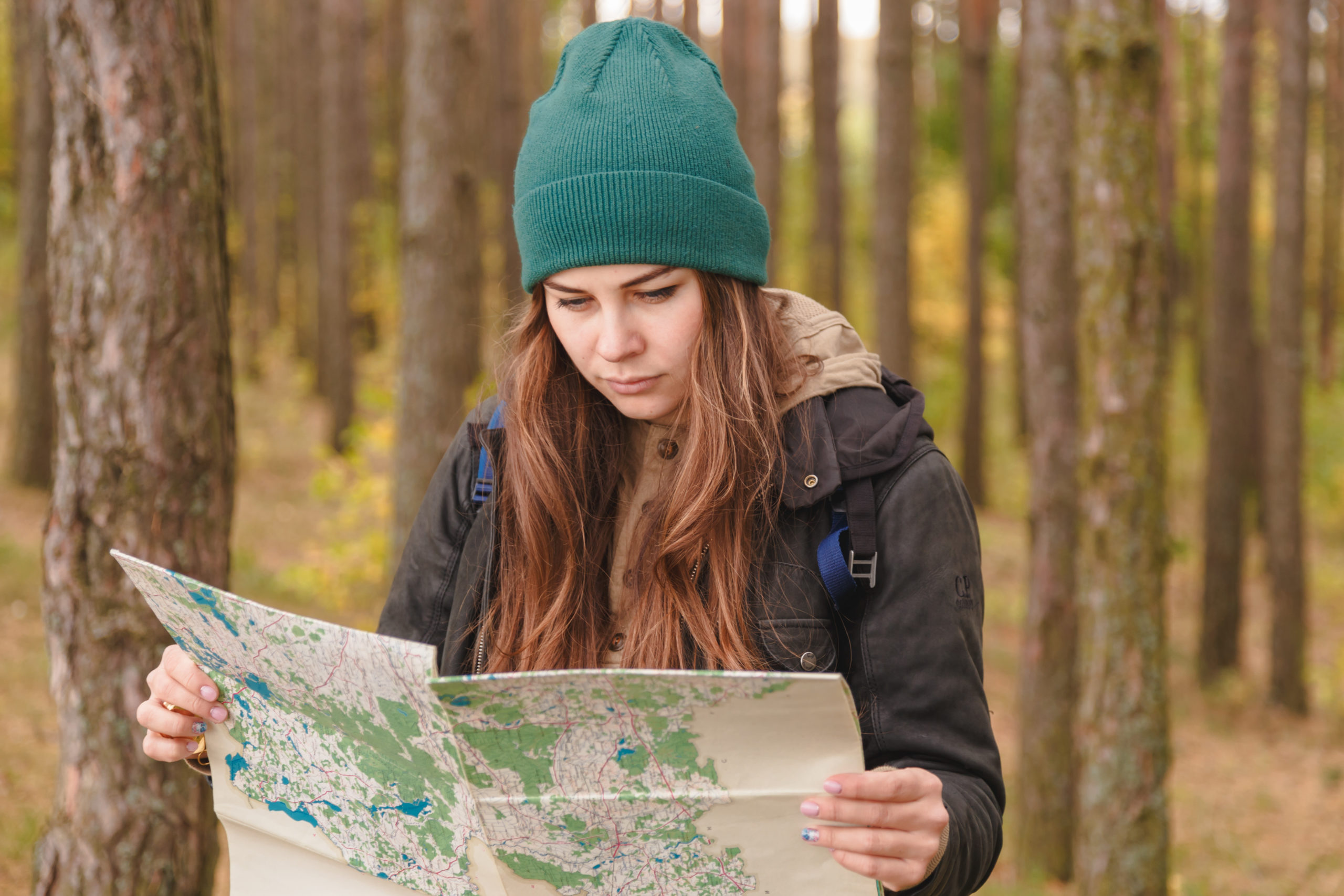 Nainen lukee karttaa metsässä.