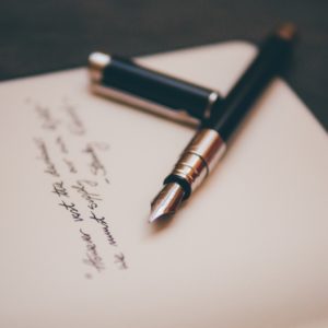 kaunokirjoitusta paperilla ja kynä