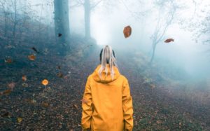 Kuvituskuva: keltaiseen sadetakkiin pukeutunut tyttö syksyisessä metsässä.
