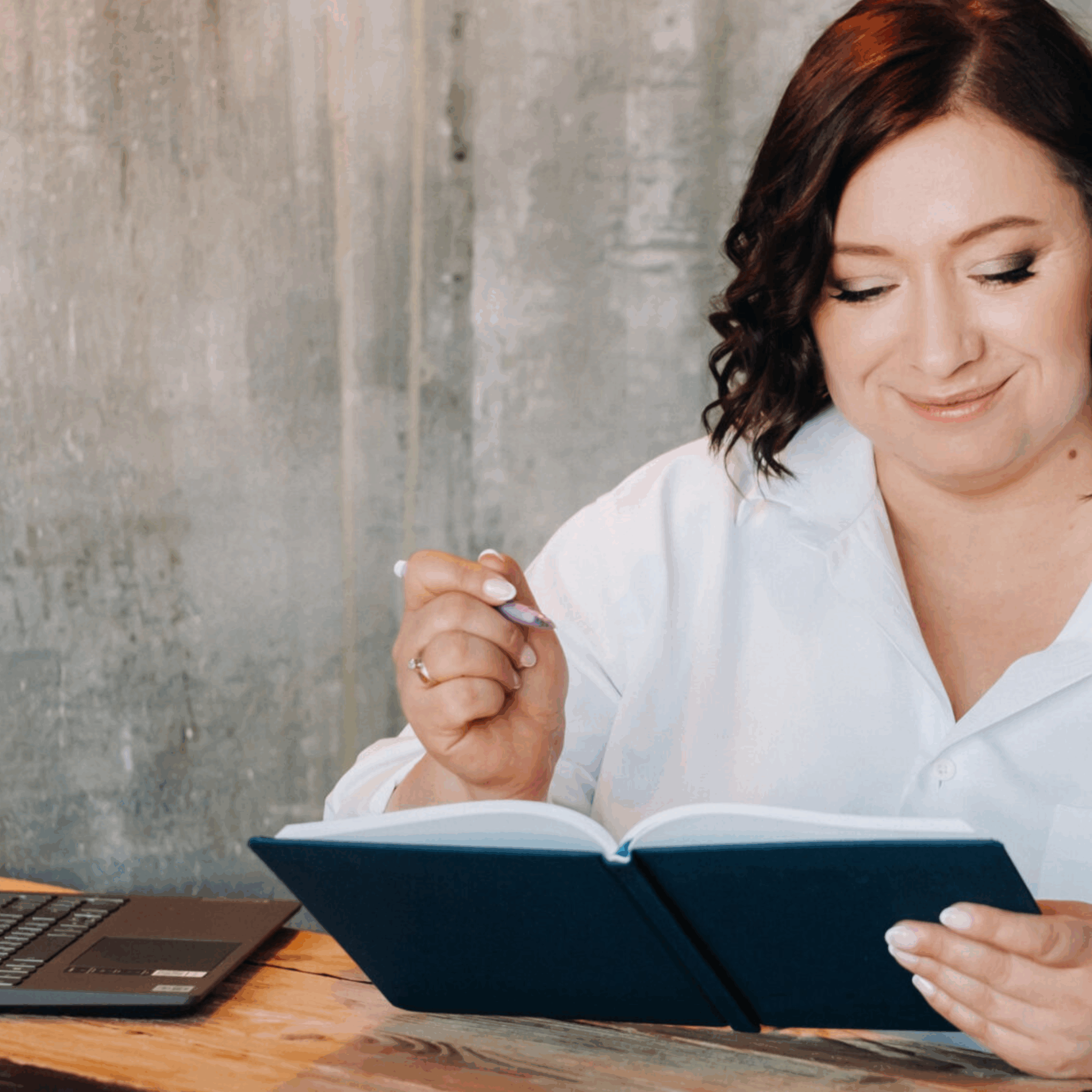 Kuvituskuva: nainen kynä kädessä kirjoittamassa mustaan muistikirjaan.